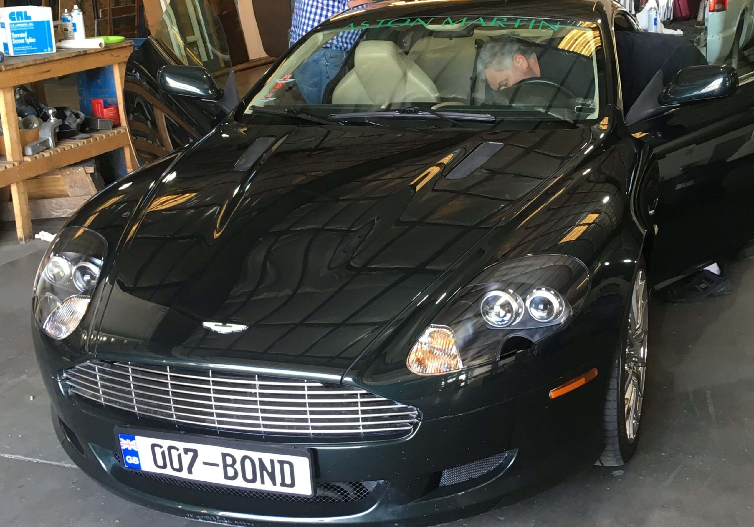 A black aston martin parked in front of a man.